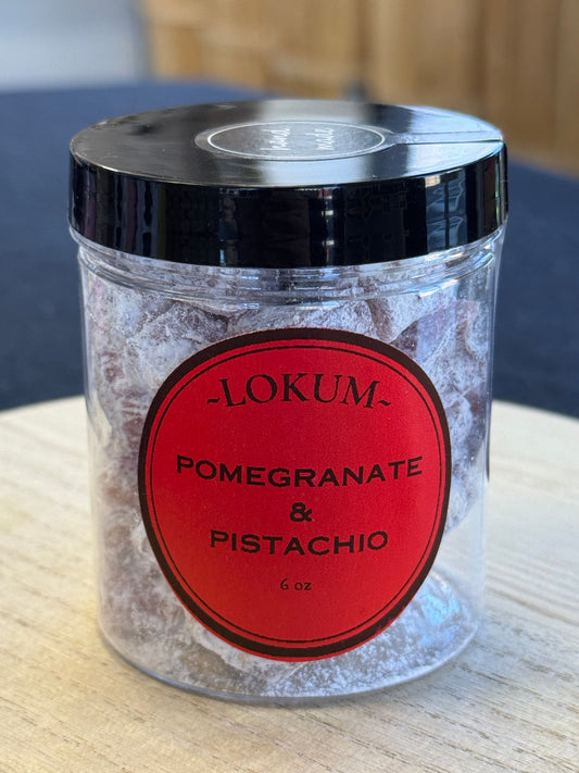 A clear jar containing pistachio-filled Turkish delight cubes with pomegranate flavor, labeled 'LOKUM Pomegranate & Pistachio'.