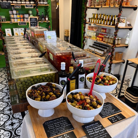 Setup with bottles of olive oils and olives on a wooden counter.